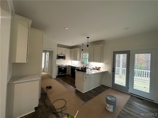 kitchen with stainless steel microwave, hanging light fixtures, electric range oven, white cabinets, and a peninsula