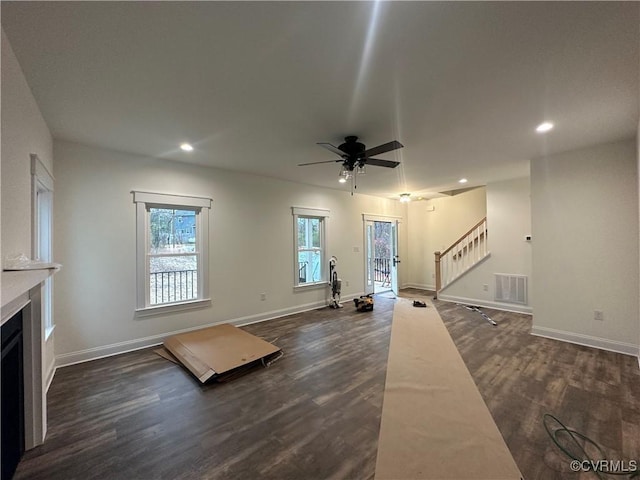 unfurnished living room featuring dark wood finished floors, visible vents, a fireplace, and stairway