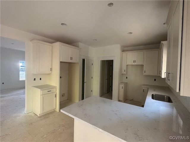 kitchen featuring light countertops, white cabinets, a sink, and a peninsula