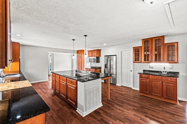 kitchen with dark wood finished floors, glass insert cabinets, a center island, stainless steel appliances, and a sink