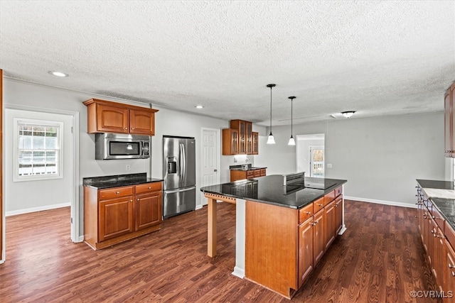 kitchen with a textured ceiling, a center island, dark hardwood / wood-style flooring, and stainless steel appliances