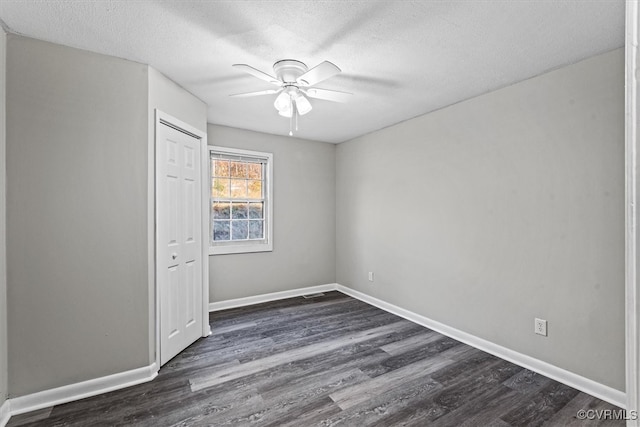 empty room with a textured ceiling, dark hardwood / wood-style flooring, and ceiling fan