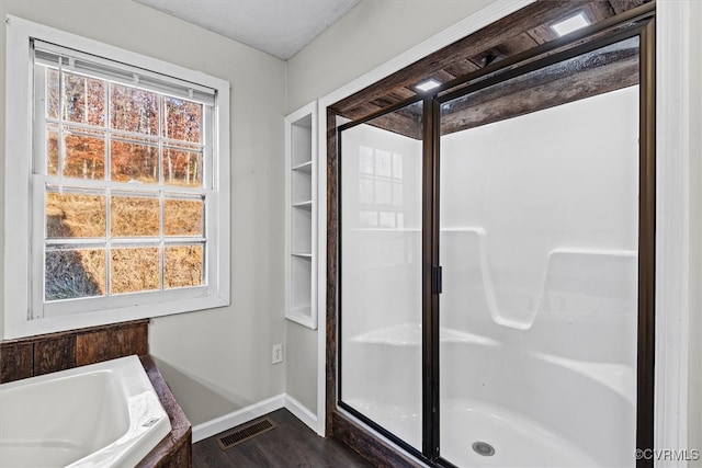 bathroom with wood-type flooring and shower with separate bathtub