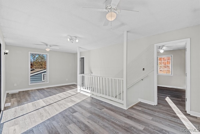 empty room with a textured ceiling, baseboards, and wood finished floors