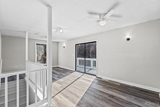 spare room featuring a wealth of natural light, ceiling fan, dark wood-type flooring, and a textured ceiling