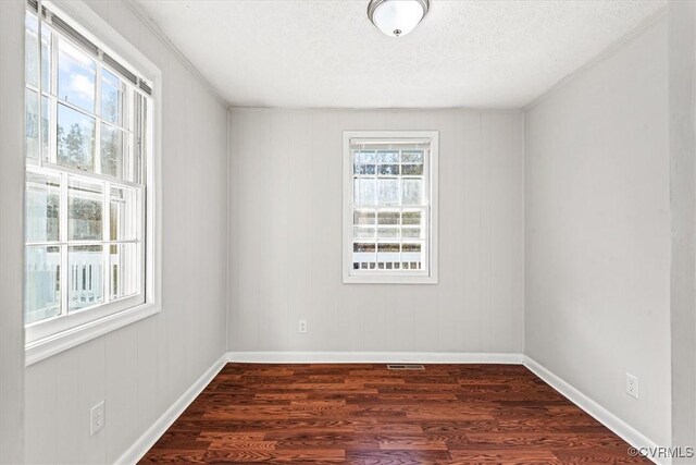 unfurnished room with dark wood-style floors, baseboards, and a textured ceiling