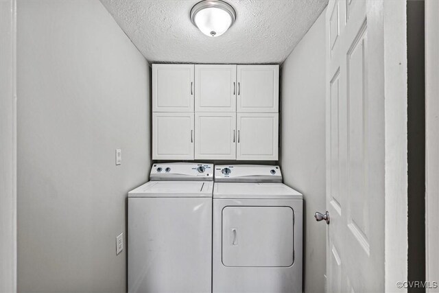 laundry area featuring cabinets, washer and dryer, and a textured ceiling