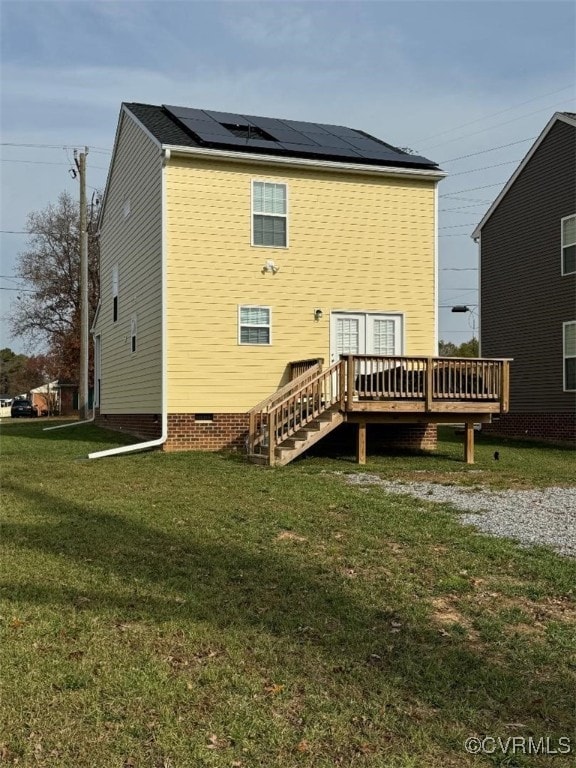 rear view of property featuring crawl space, a yard, a wooden deck, and solar panels