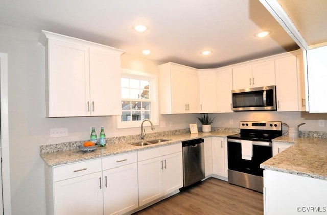 kitchen with stainless steel appliances, light wood-type flooring, a sink, and white cabinetry