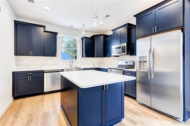 kitchen featuring appliances with stainless steel finishes, light wood-type flooring, sink, pendant lighting, and a kitchen island