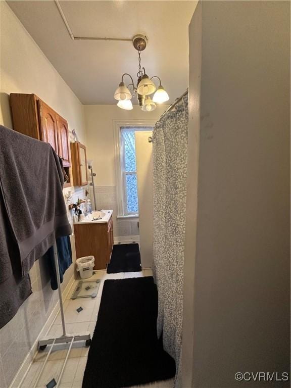 bathroom with tile patterned flooring, vanity, a shower with shower curtain, and a notable chandelier