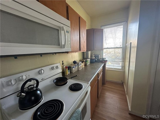 kitchen with light wood-type flooring, white appliances, and tasteful backsplash