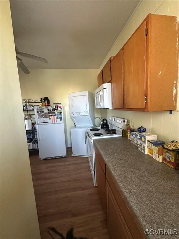 kitchen with ceiling fan, stacked washer and dryer, dark wood-type flooring, and white appliances