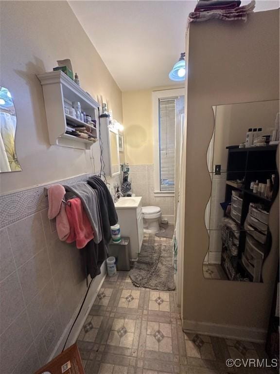 bathroom featuring vanity, toilet, and tile walls