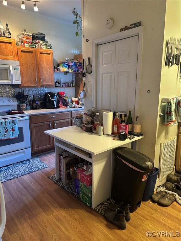 kitchen with tasteful backsplash, white appliances, and hardwood / wood-style flooring