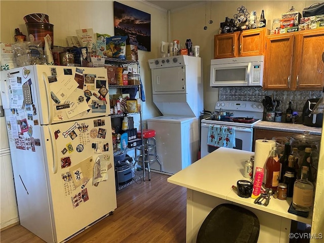 kitchen featuring backsplash, stacked washing maching and dryer, white appliances, and hardwood / wood-style flooring