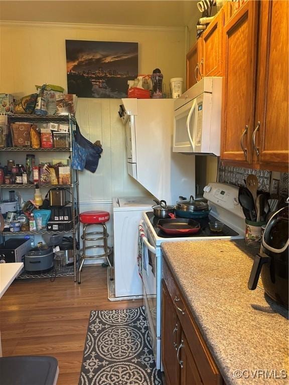 kitchen with white appliances, dark hardwood / wood-style floors, and crown molding