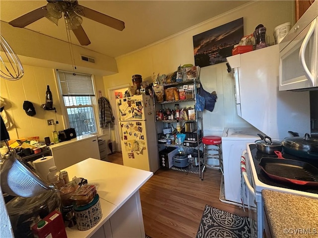 kitchen with dark hardwood / wood-style flooring, white appliances, washer / clothes dryer, and ceiling fan