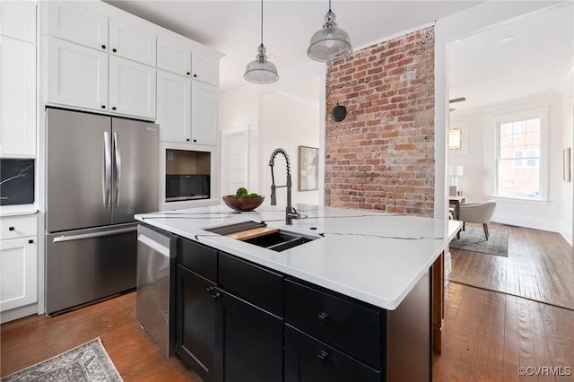 kitchen featuring appliances with stainless steel finishes, hardwood / wood-style floors, light countertops, white cabinetry, and a sink