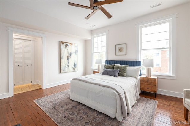 bedroom featuring wood-type flooring, visible vents, ceiling fan, and baseboards