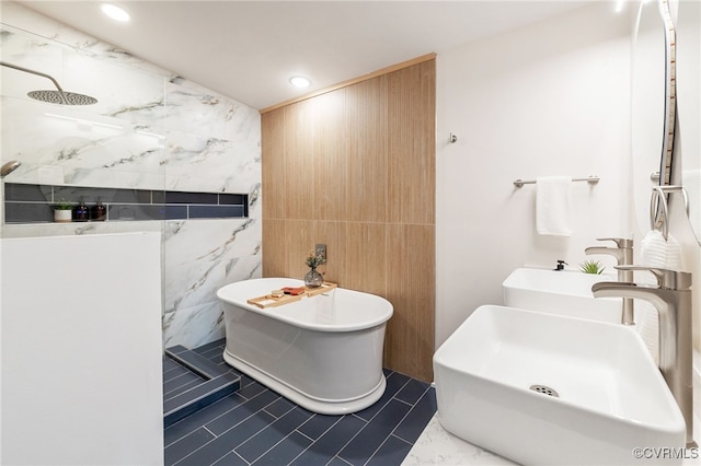 full bath featuring a soaking tub, dual sinks, a walk in shower, tile walls, and recessed lighting