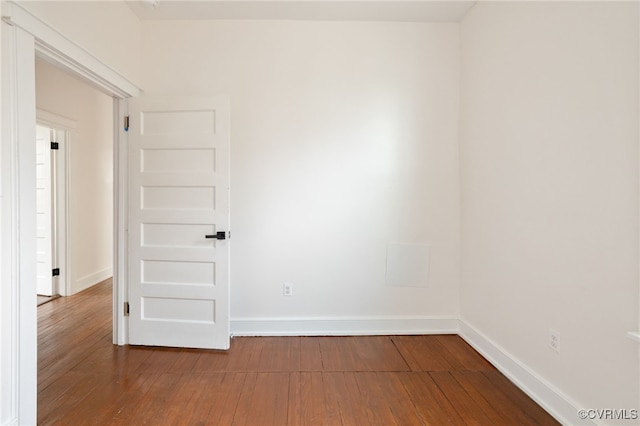 spare room featuring wood-type flooring and baseboards