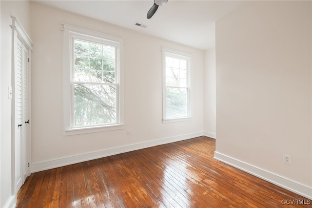 unfurnished room featuring a ceiling fan, hardwood / wood-style flooring, visible vents, and baseboards