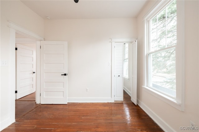 unfurnished bedroom featuring baseboards, multiple windows, and hardwood / wood-style floors