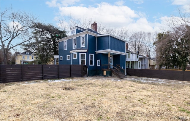 rear view of house featuring a chimney and fence