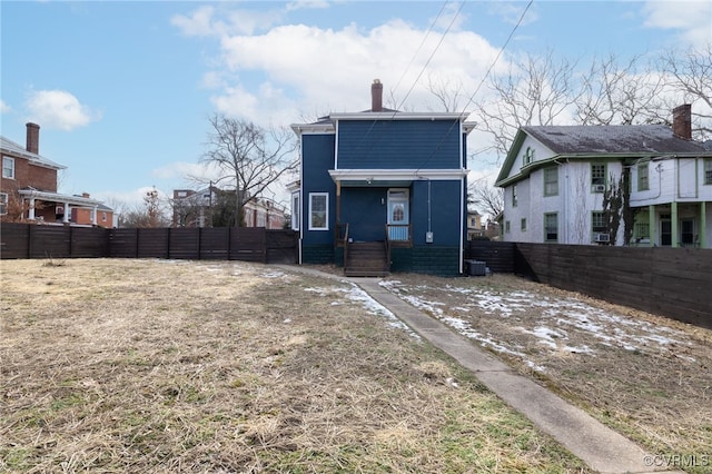 rear view of house featuring a fenced backyard and a chimney