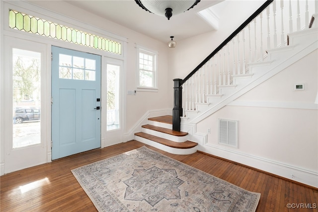 entrance foyer with stairs, visible vents, and wood finished floors