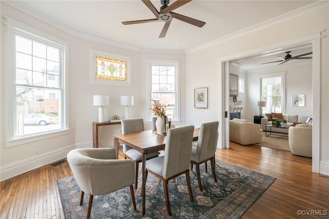 dining space with ornamental molding, wood-type flooring, visible vents, and baseboards