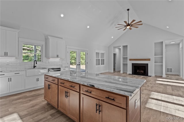 kitchen featuring a center island, sink, a wealth of natural light, light hardwood / wood-style floors, and white cabinetry