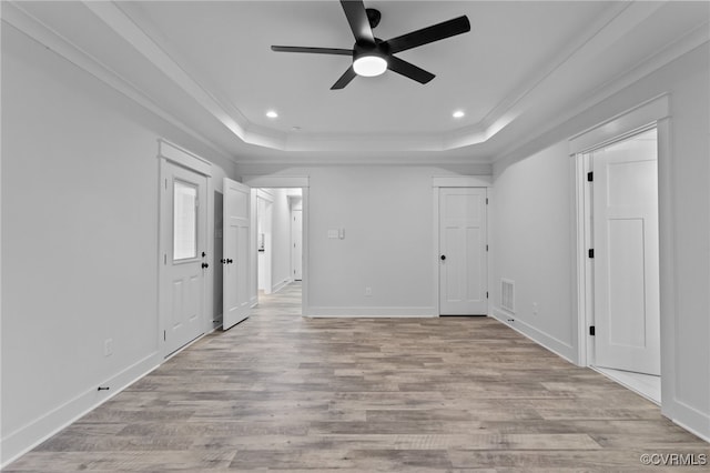 unfurnished room featuring a tray ceiling, ceiling fan, and light hardwood / wood-style floors