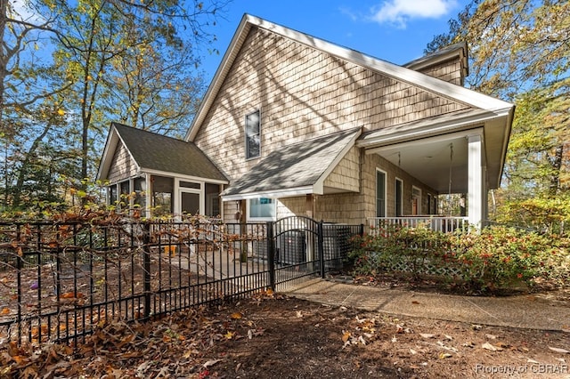 back of house with a sunroom, covered porch, and central air condition unit