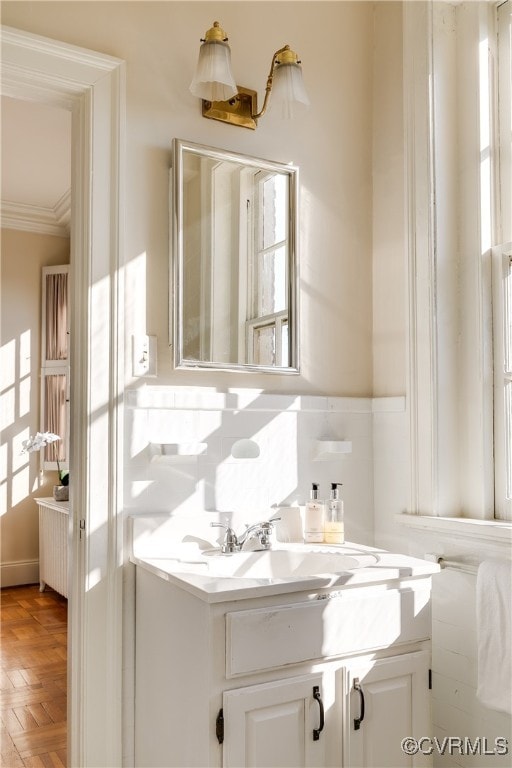 bathroom with parquet flooring, vanity, and ornamental molding