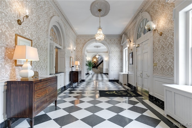 hall with a notable chandelier and ornamental molding