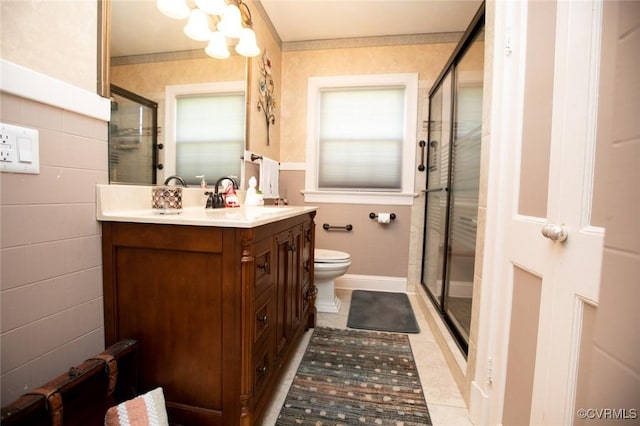 bathroom featuring vanity, tile patterned floors, toilet, tile walls, and a shower with shower door