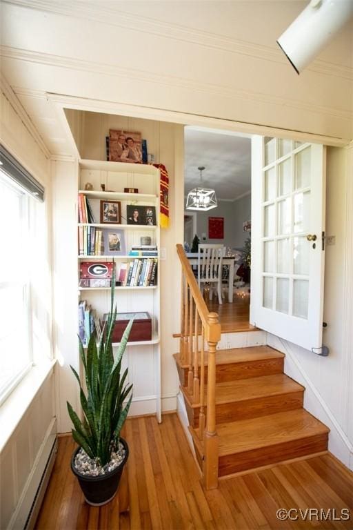 stairway featuring hardwood / wood-style flooring, baseboard heating, and ornamental molding