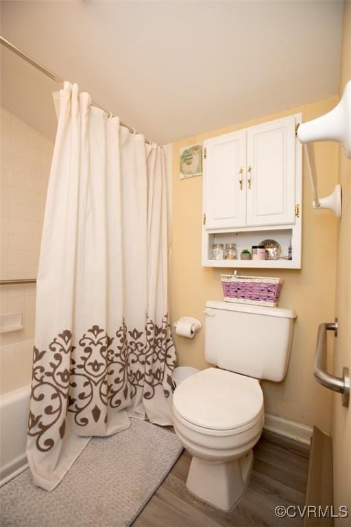 bathroom with hardwood / wood-style floors, shower / bathtub combination with curtain, and toilet