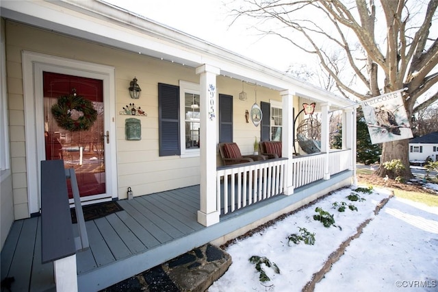 snow covered property entrance featuring a porch