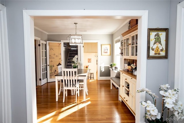 dining area with hardwood / wood-style flooring, crown molding, and an inviting chandelier