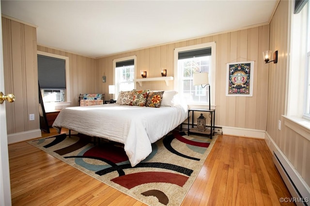 bedroom featuring light hardwood / wood-style floors, cooling unit, and a baseboard heating unit