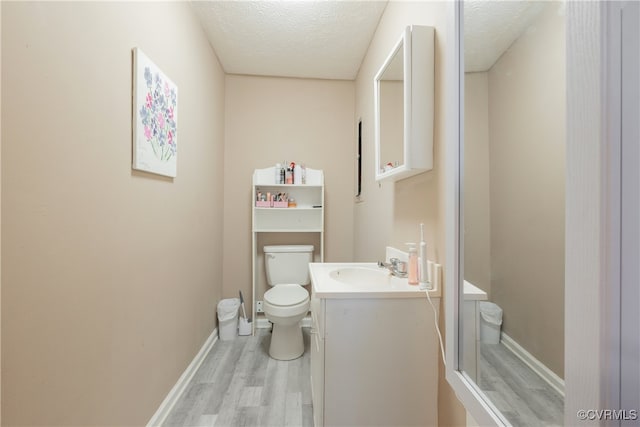 bathroom with hardwood / wood-style flooring, vanity, toilet, and a textured ceiling