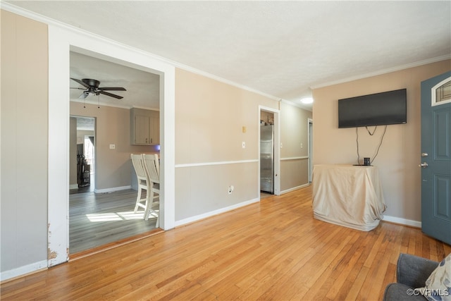 unfurnished living room with crown molding, ceiling fan, and light wood-type flooring