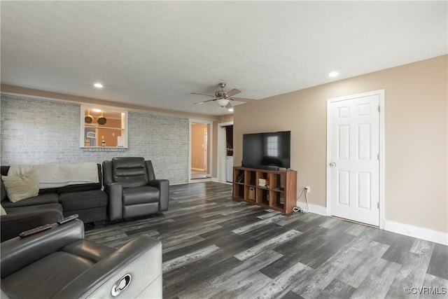 living room with dark hardwood / wood-style floors, ceiling fan, and brick wall