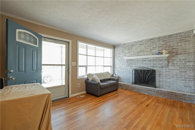 unfurnished living room with hardwood / wood-style flooring, a fireplace, brick wall, and a textured ceiling