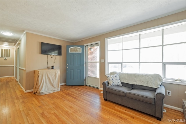 living room featuring light hardwood / wood-style floors, a textured ceiling, and ornamental molding