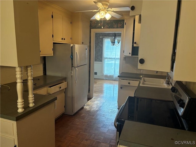 kitchen featuring sink, white appliances, decorative backsplash, white cabinets, and ceiling fan with notable chandelier