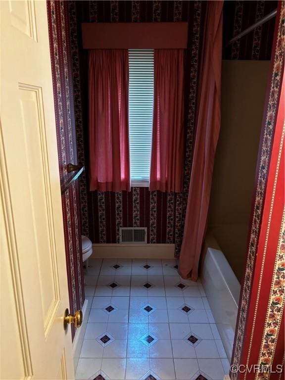 bathroom with tile patterned flooring, toilet, and shower / tub combo